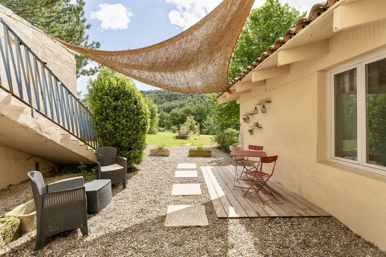 Terrasse privée du gîte Le Laurier sous la voile d'ombrage, vue sur la colline