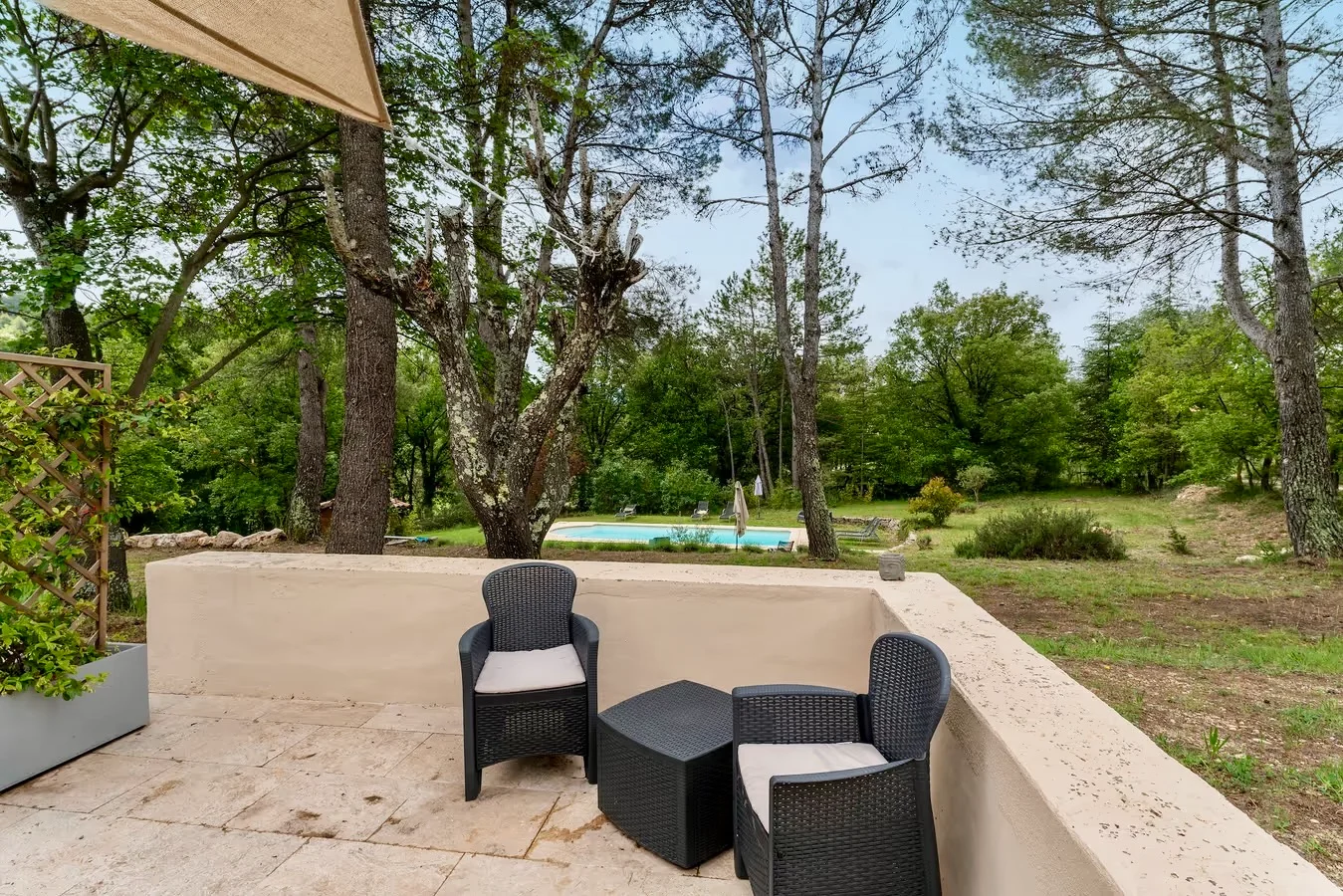 Terrasse avec fauteuils et vue sur la piscine à travers les pins